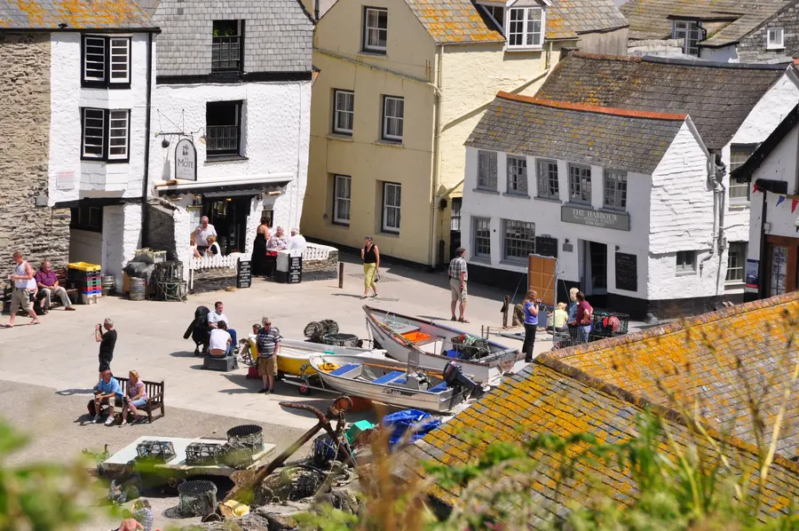 Whitewashed slate-roofed cottages around an open harbour front with small boats and lobster pots