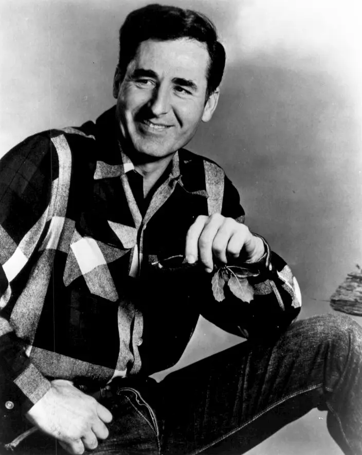 Black-and-white publicity portrait of Sheb Wooley in a checked shirt, smiling